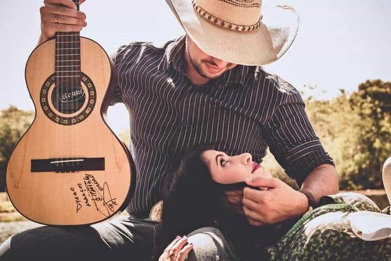 man holding a guitar and looking at woman