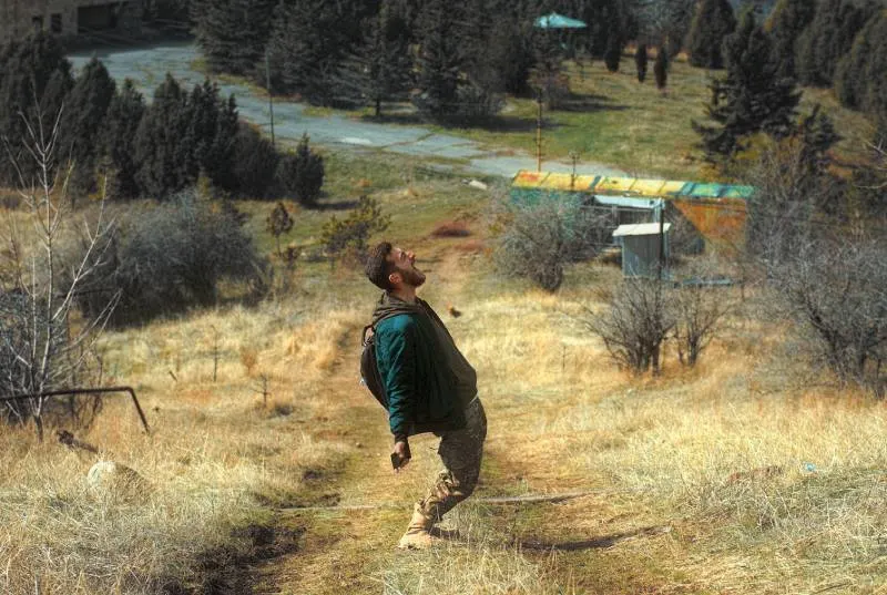 man in green jacket walking on brown field during daytime