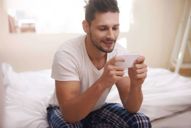 man sitting and typing on his phone in the morning