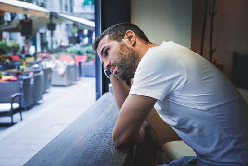 man thinking by the window and leaning on hand