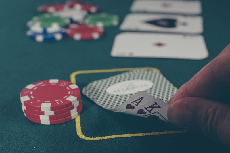 persona che tiene in mano l'asso nero e il re di picche giocando a carte sul tavolo da poker