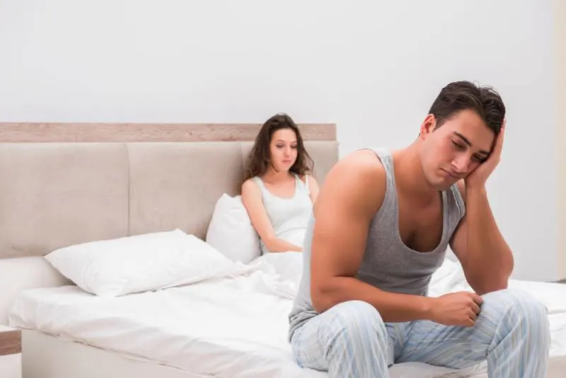 sad couple sitting on bed in bedroom
