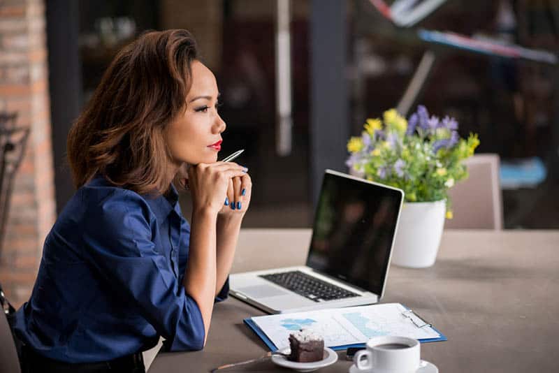 side view of beautiful woman sitting on table with laptop