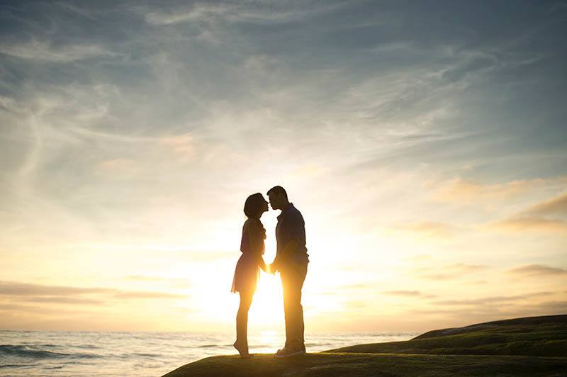 silhouette of couple kisses on sunset