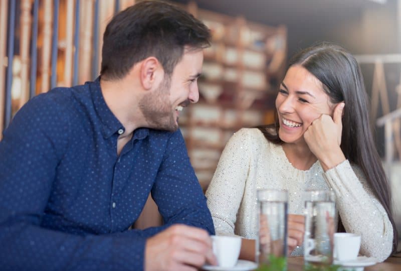 pareja sonriente disfrutando de un café en una cafetería