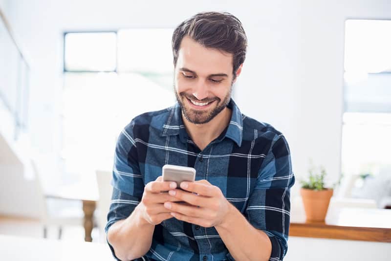 hombre sonriente enviando mensajes de texto