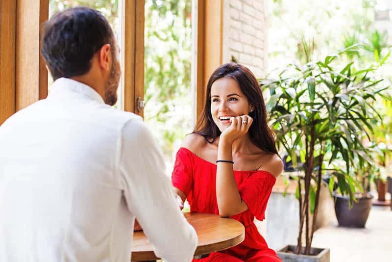 mujer sonriente con vestido rojo mirando a un hombre