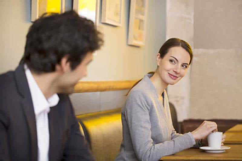 mulher sorridente a olhar para uma mulher num café