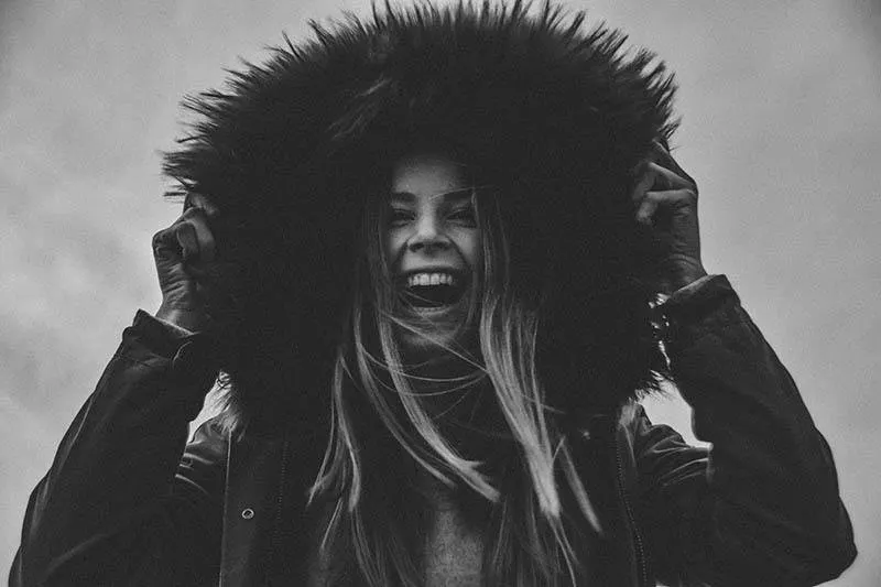 smiling woman puts hood over her head outside
