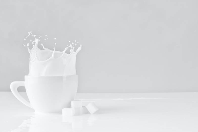 blocco di zucchero lasciato cadere su una tazza bianca con latte