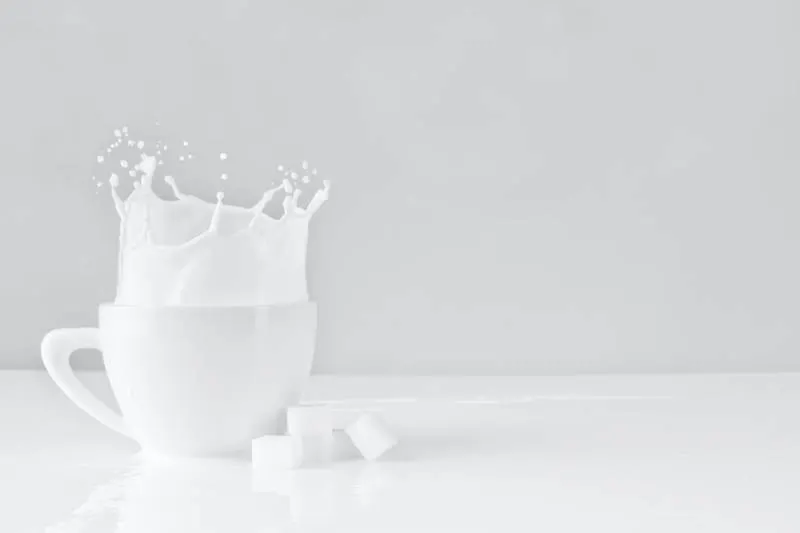 sugar block dropped on white cup with milk