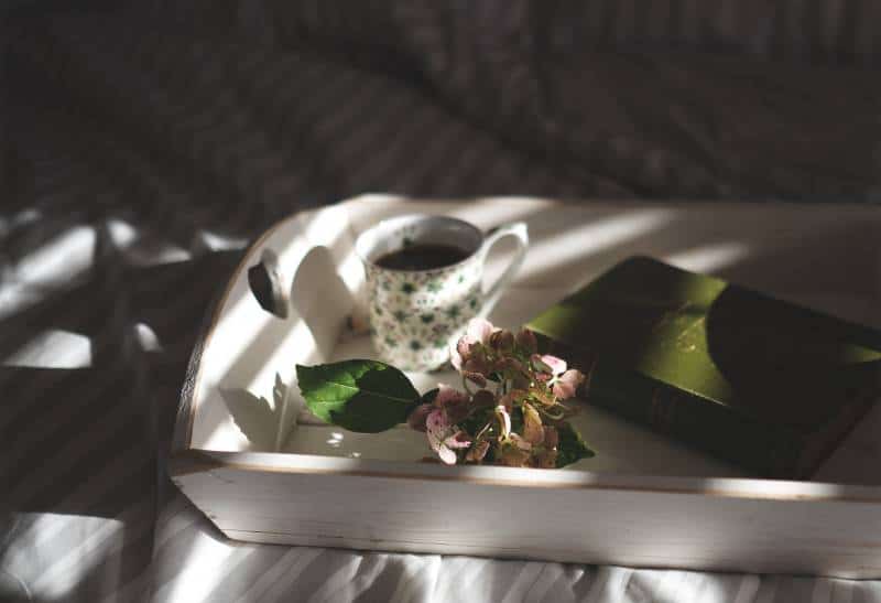 tazza da tè accanto a fiori rosa su vassoio