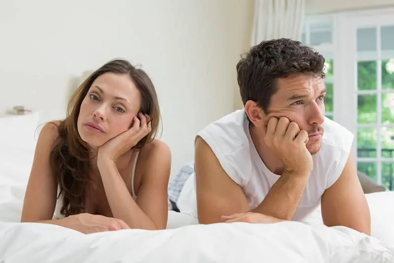 unhappy couple laying on bed