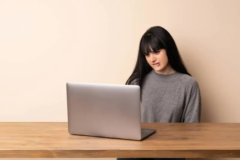 woman biting lips and looking at laptop