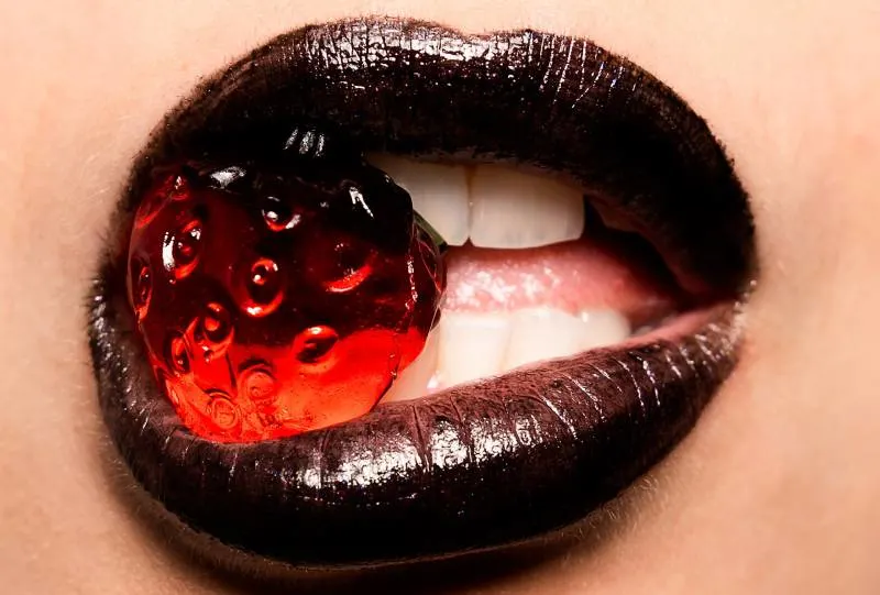 woman biting red strawberry candy