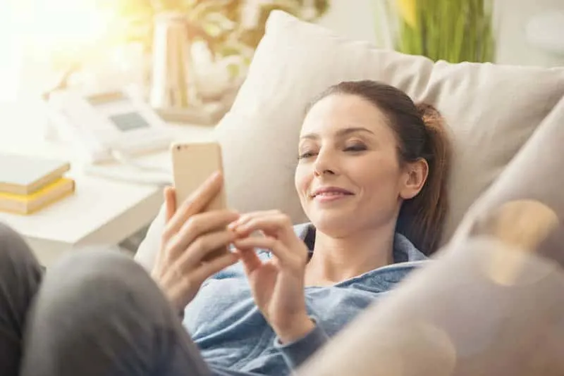 woman sitting at home and typing on her phone