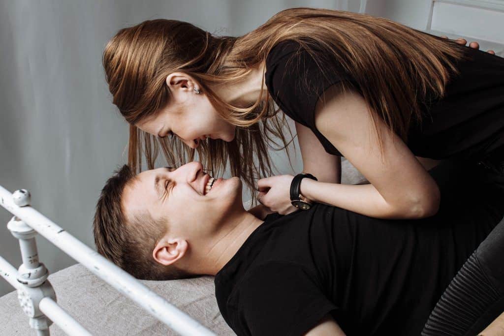 mujer hablando con hombre sonriente en la cama