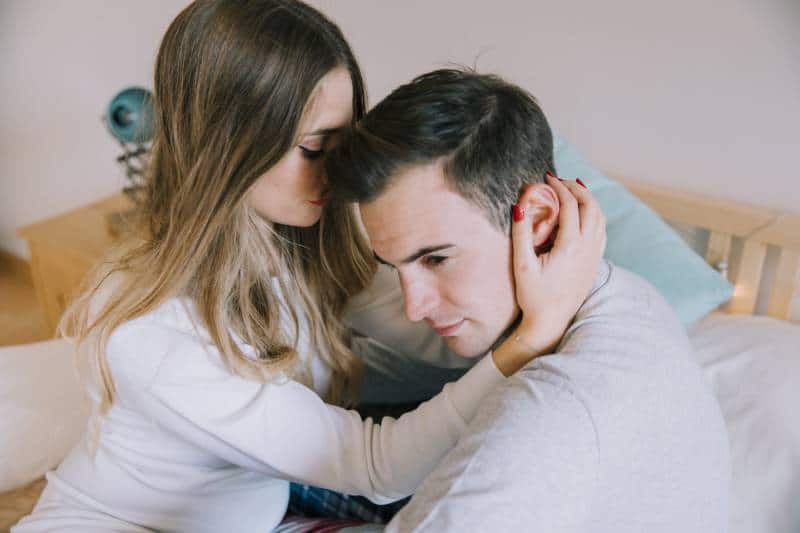 woman touching man hair in bed