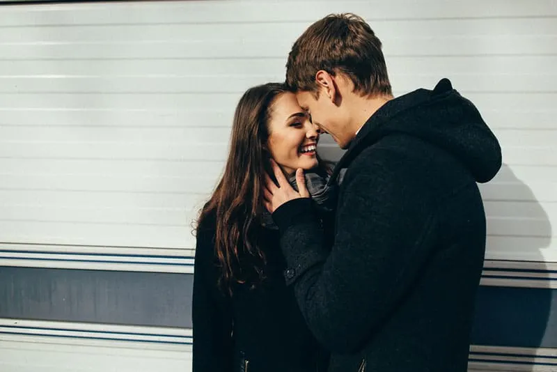 young couple smiling and cuddling outdoor