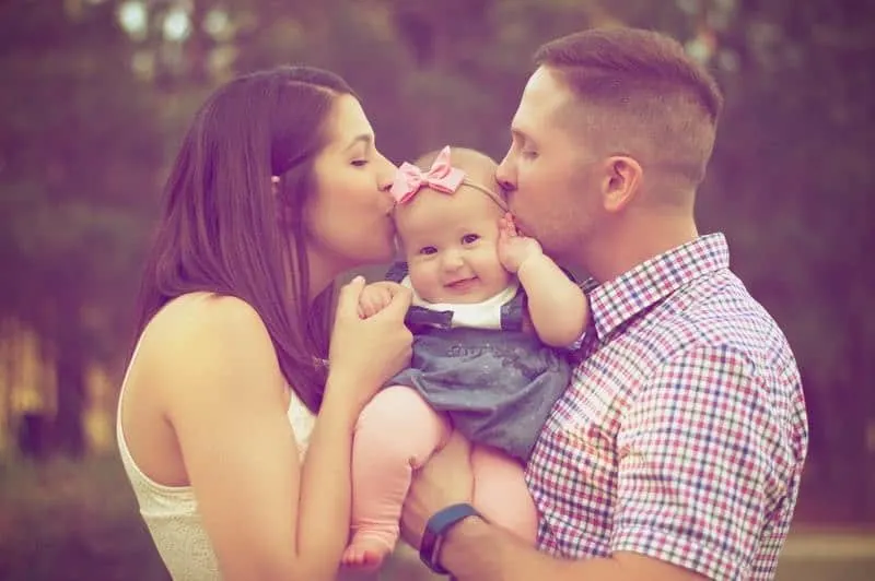 young parents kissing their baby girl