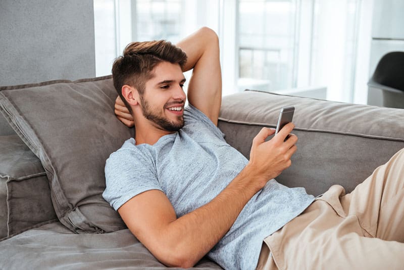 young smiling man looking at phone