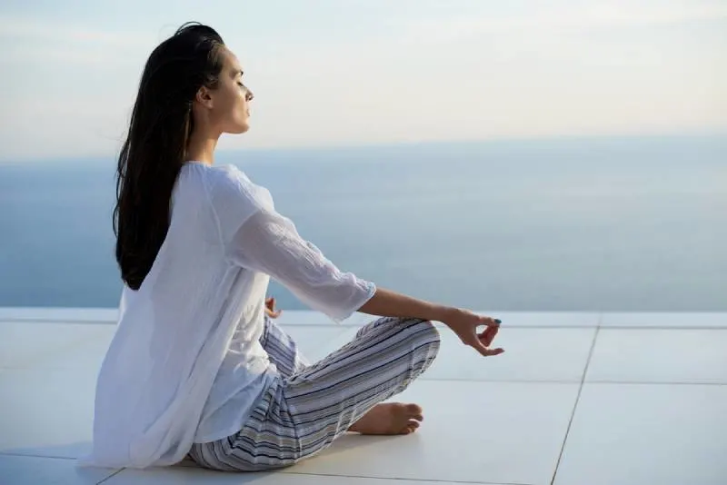 young women practice yoga meditation on sunset with ocean view in background