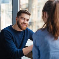 a smiling man sitting at the bar with a girl and talking