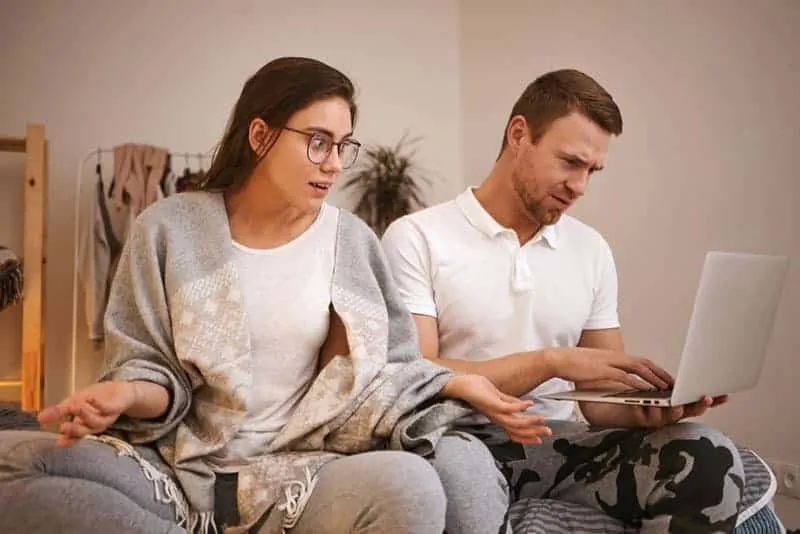 Handsome male workaholic using laptop ignoring his annoyed frustrated wife