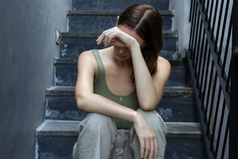 donna triste seduta sulle scale