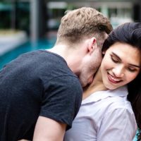 man kisses smiling woman neck