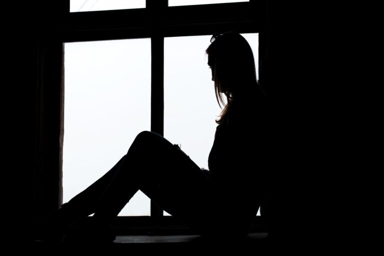 Woman looking through the old window sitting on the window sill