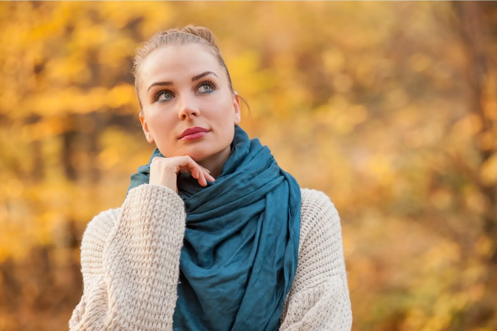 Pensive pretty woman relaxing outside in the forest in autumn day