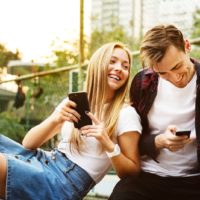 a young loving couple having fun outside with smartphones