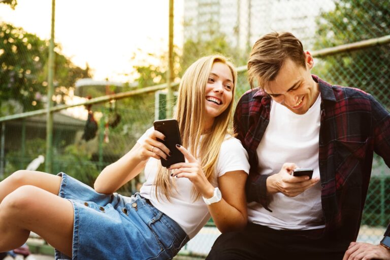a young loving couple having fun outside with smartphones