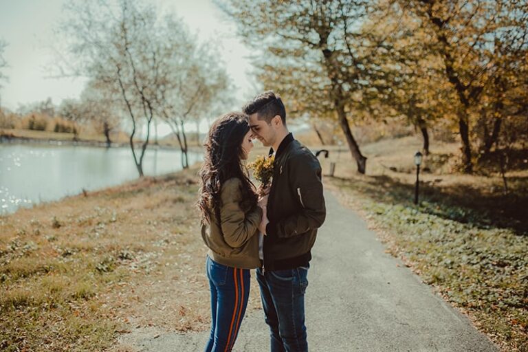 romantic couple standing face to face near lake