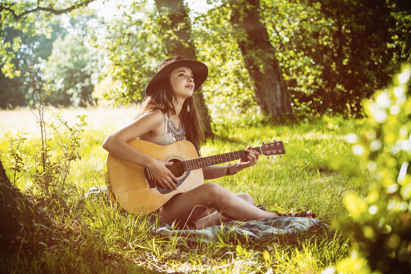 Giovane donna seduta sull'erba che suona la chitarra