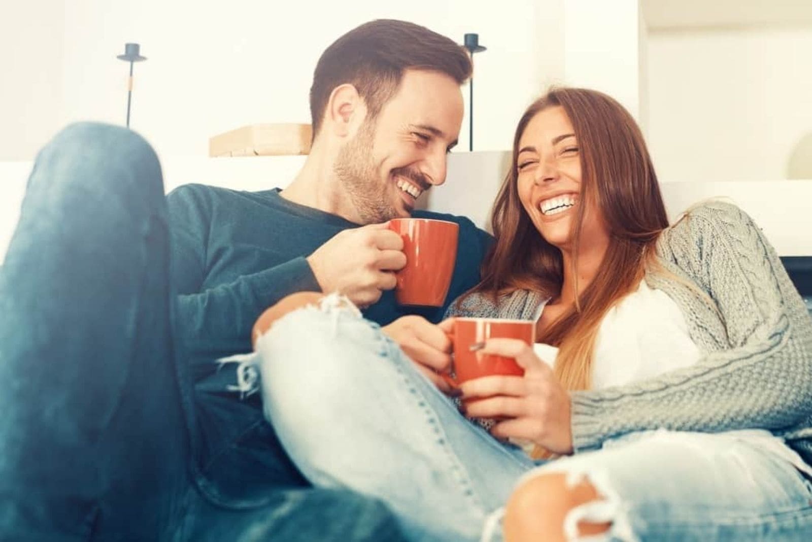 a man and a woman sit drinking coffee and laughing