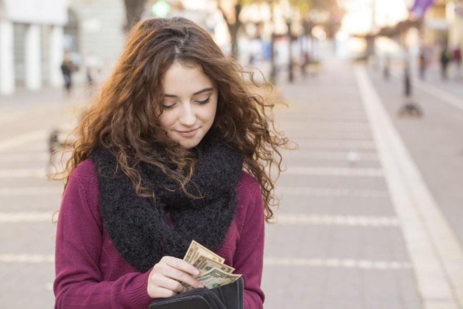 a woman with frizzy hair stands and counts the money