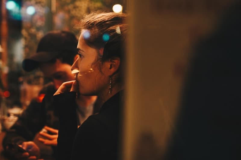 a worried woman sitting in a cafe with a man in a cap and thinking