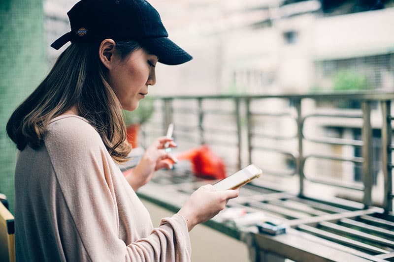 mujer asiática mirando el teléfono y fumando