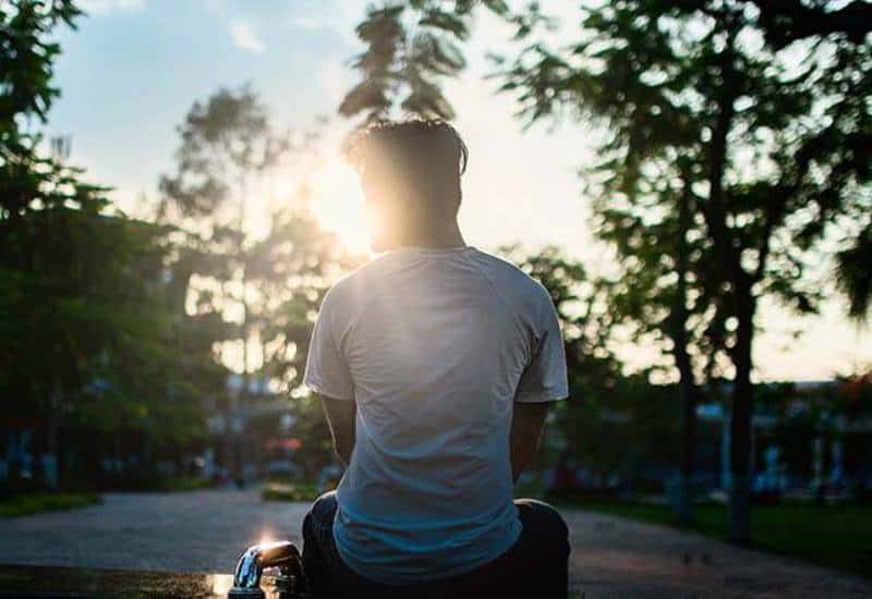 vista traseira de um homem sentado num parque enquanto