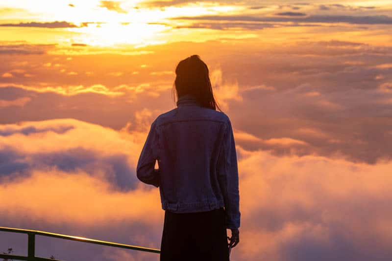 vista posteriore di una donna in piedi sulla cima di una collina