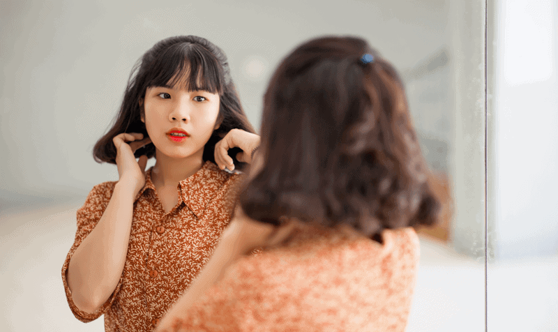 beautiful asian woman looking at mirror