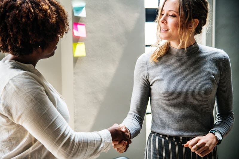 black and white women in the office shake hands