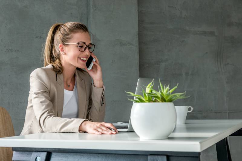  femme d'affaires qui reçoit un appel assise à son bureau