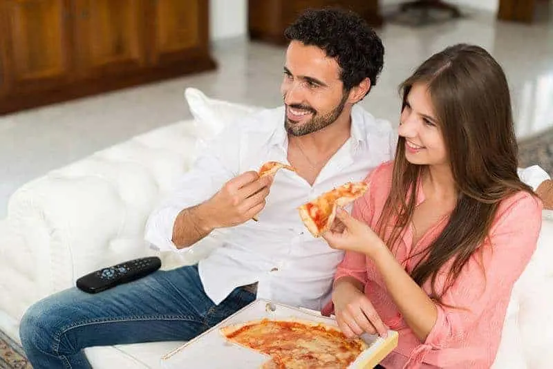 couple eating pizza while watching TV