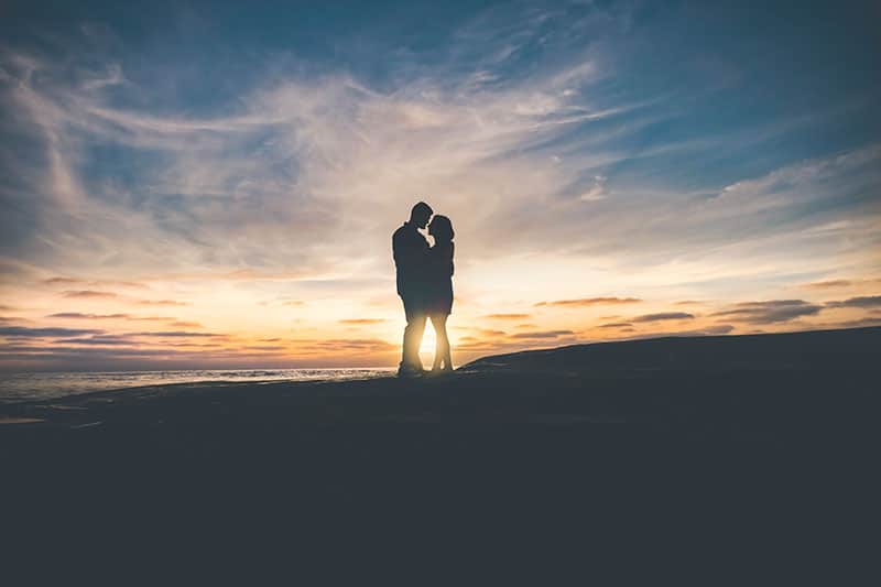 pareja romántica de pie en la puesta de sol