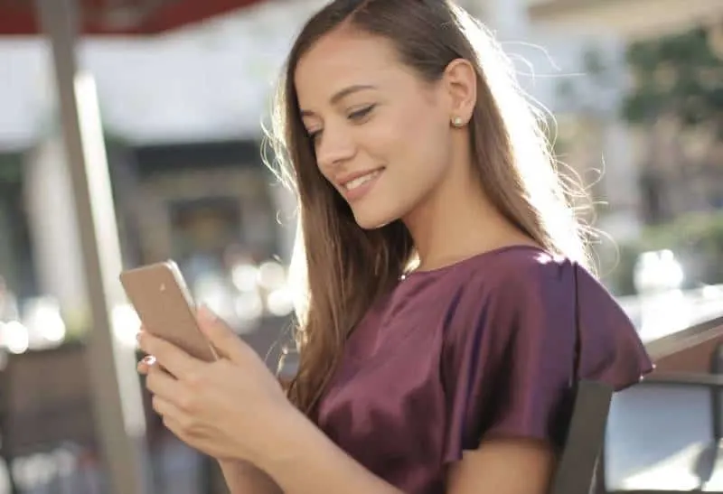 cute woman looking at her phone outside