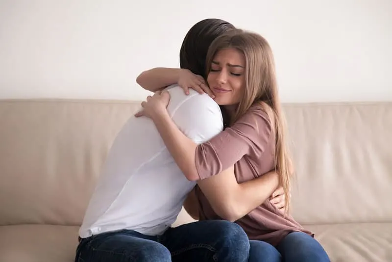 emotional couple hugging on sofa