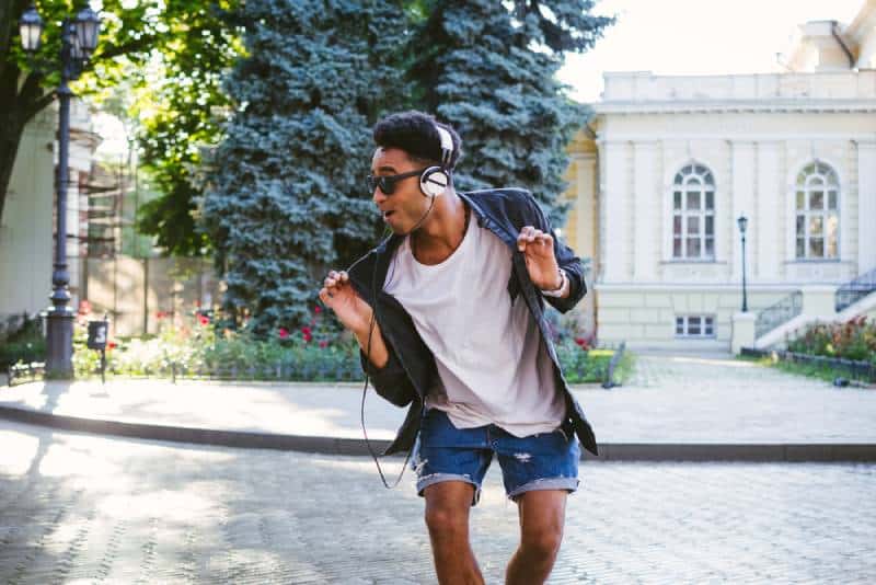 hipster man in white headphones and sunglasses dancing outdoor